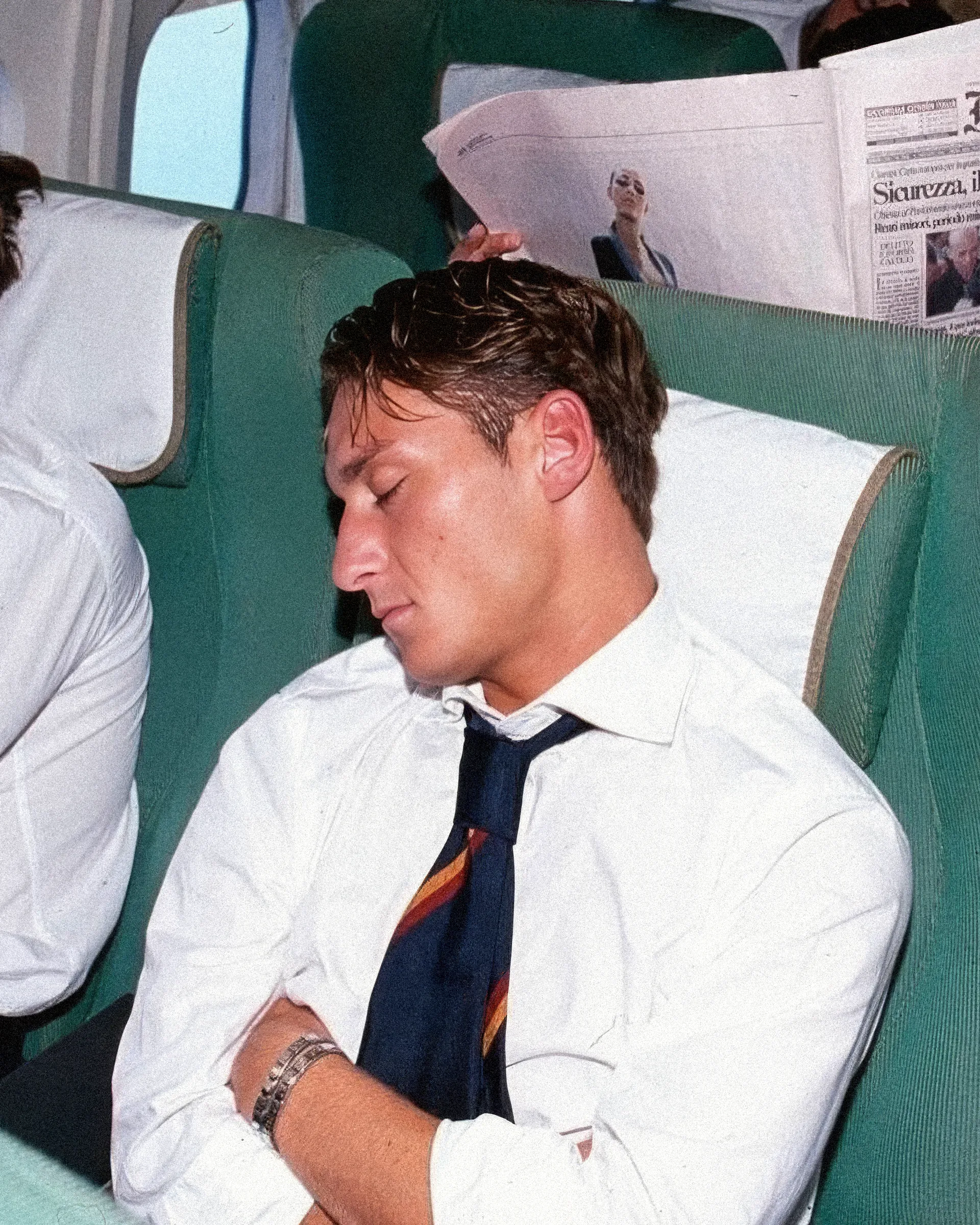 Un uomo dorme in aereo, camicia bianca e cravatta.