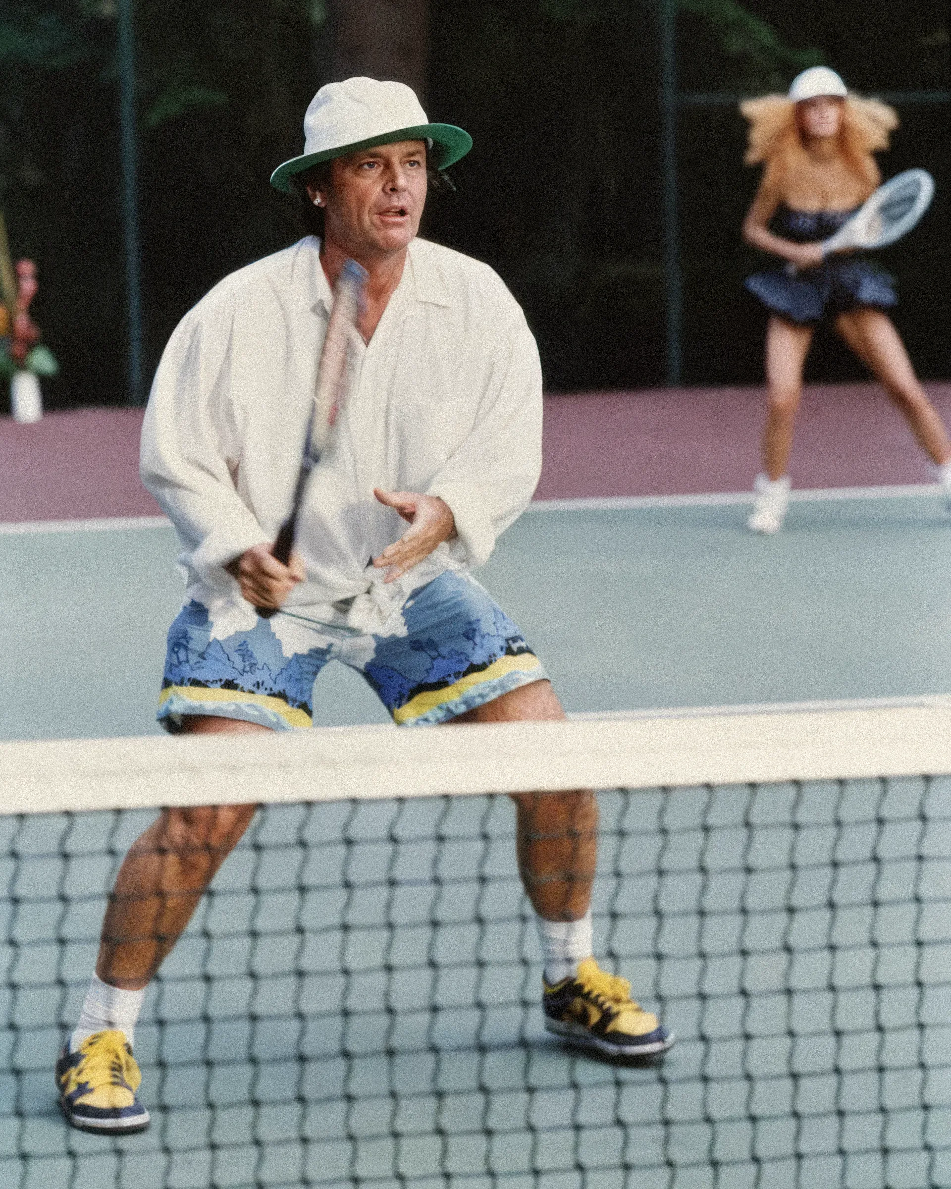 Un uomo con un cappello da pescatore gioca a tennis.